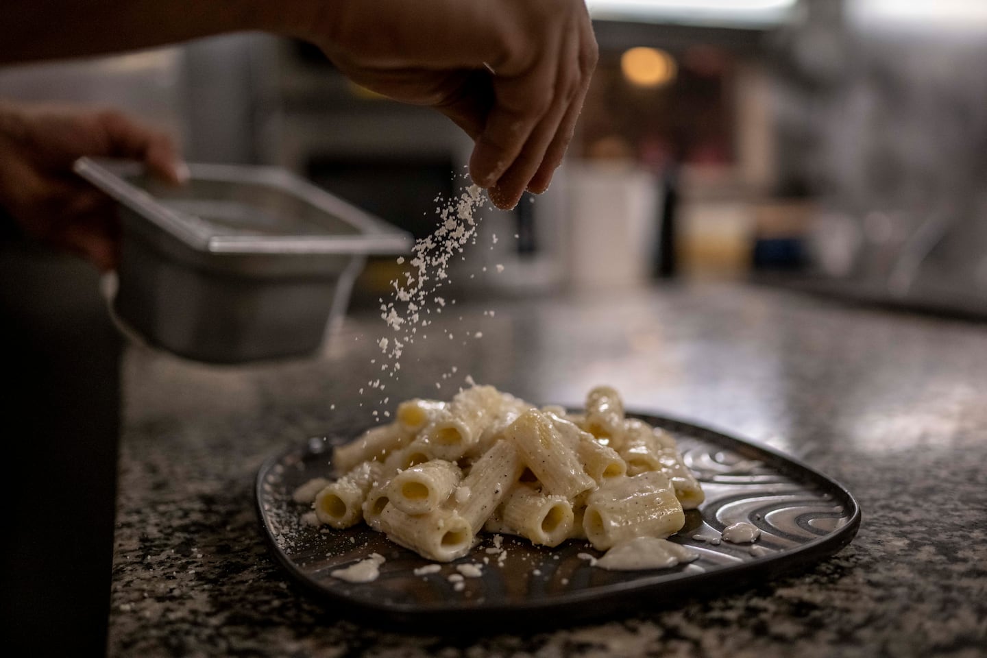Chef Giuseppe Bello sprinkles parmesan cheese on pasta "Grisia" During dinner at Saltimbocca restaurant.