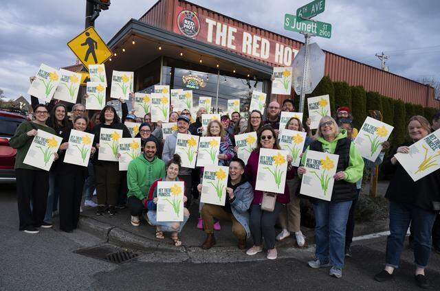 Fans hold up and pose with their copies of posters made by Beautiful Angle, a Tacoma-based guerrila letterpress poster projected founded by Lance Kagey and Tom Llewellyn, outside The Red Hot, on Tuesday, March 31, 2026, in Tacoma.