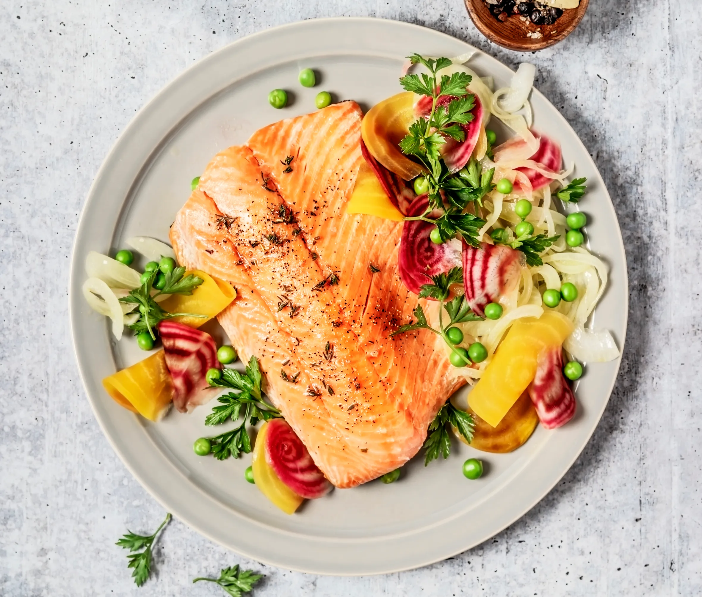 Stir-fried salmon and vegetables on a gray background.