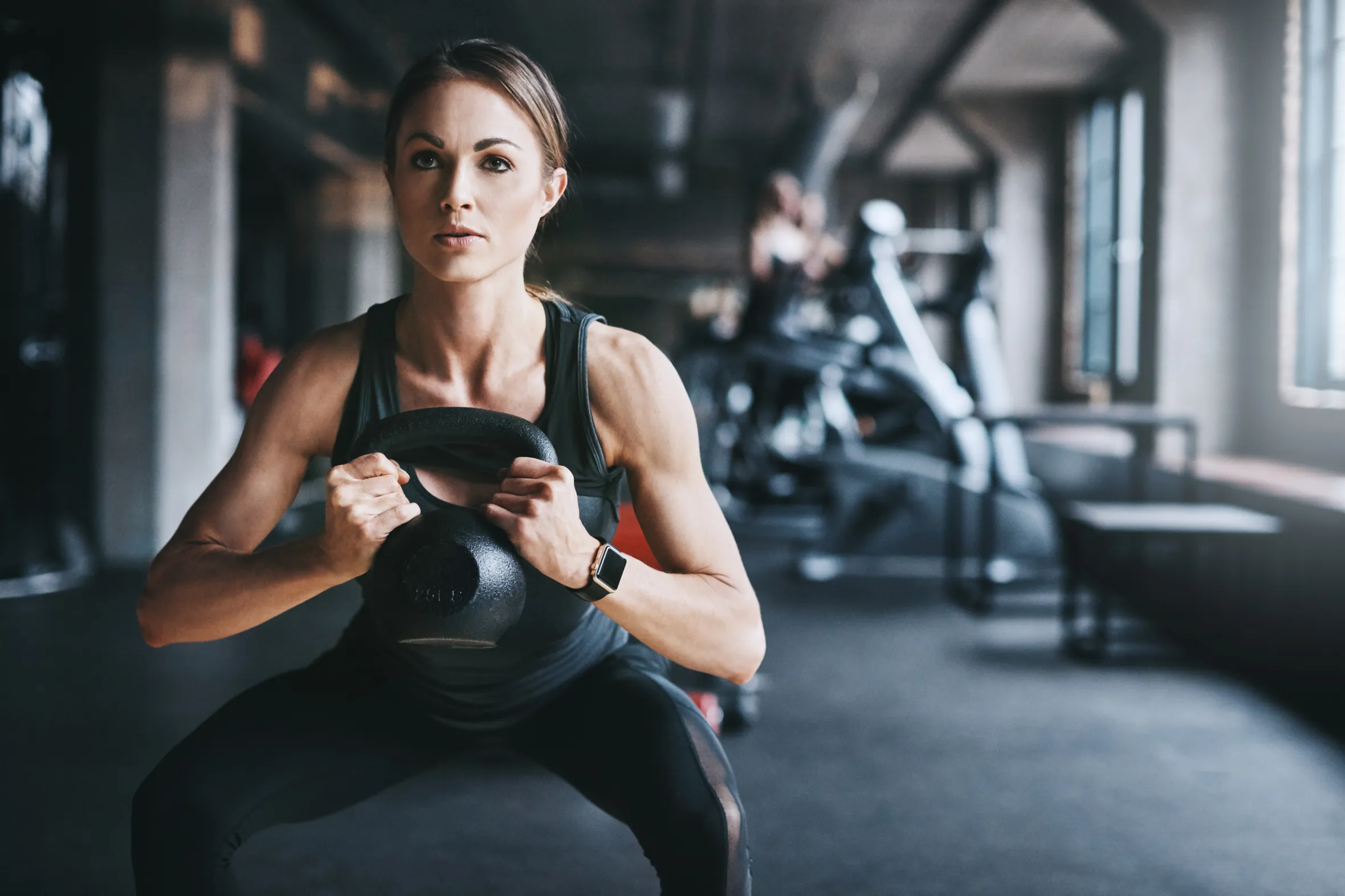 Young woman in the gym training with kettlebell.
