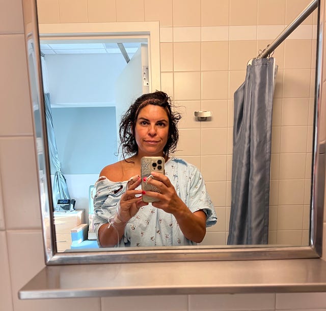 A person takes a selfie in the mirror in a medical setting.