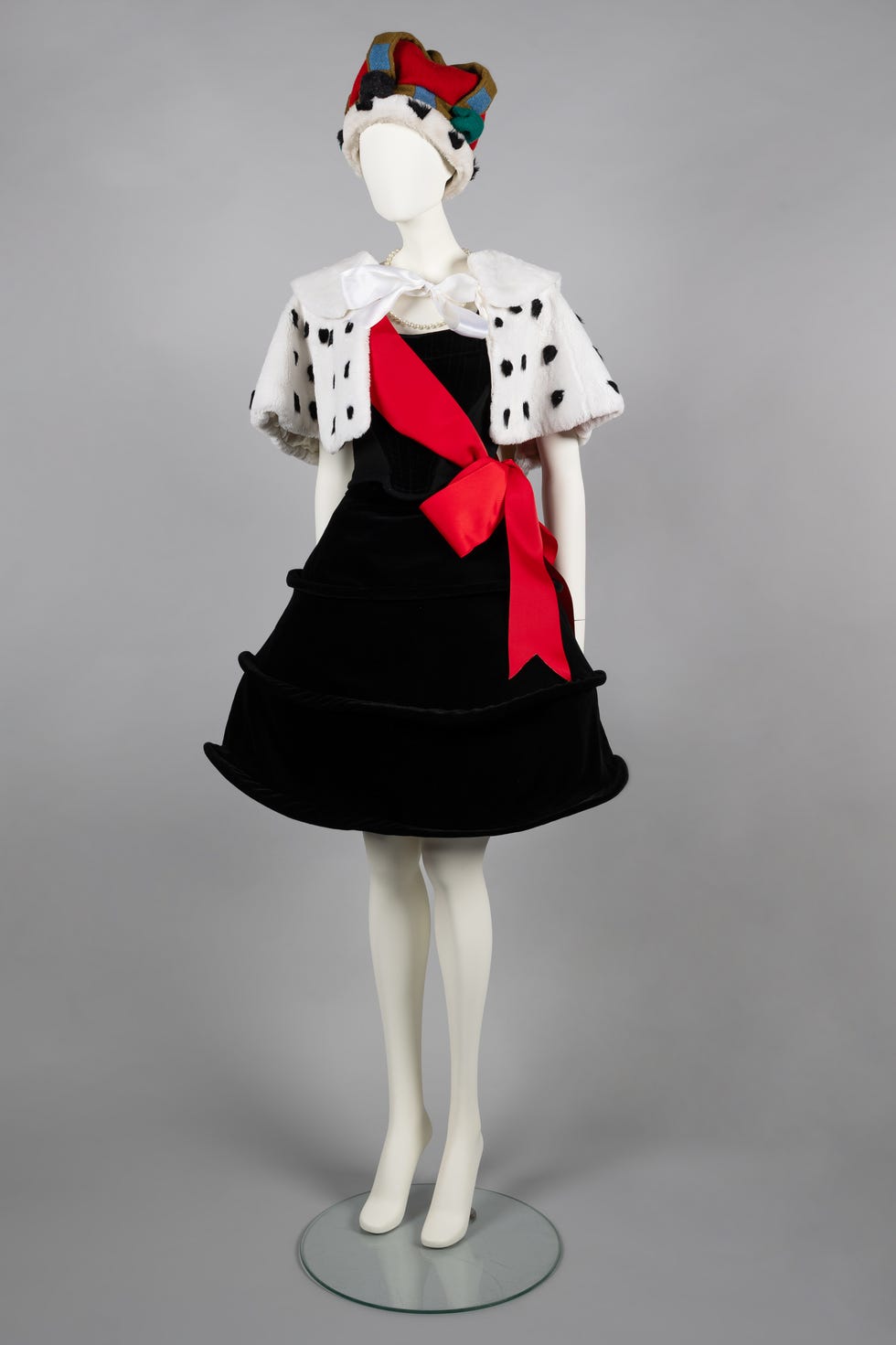Mannequin costume featuring a black dress with a red sash and fur cape