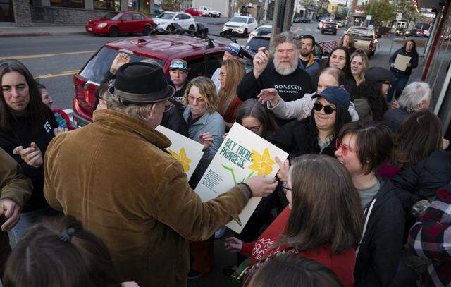 Lance Kagey, one half of Beautiful Angle, a Tacoma-based guerrila letterpress poster projected, hands out posters to waiting fans outside The Red Hot, on Tuesday, March 31, 2026, in Tacoma.