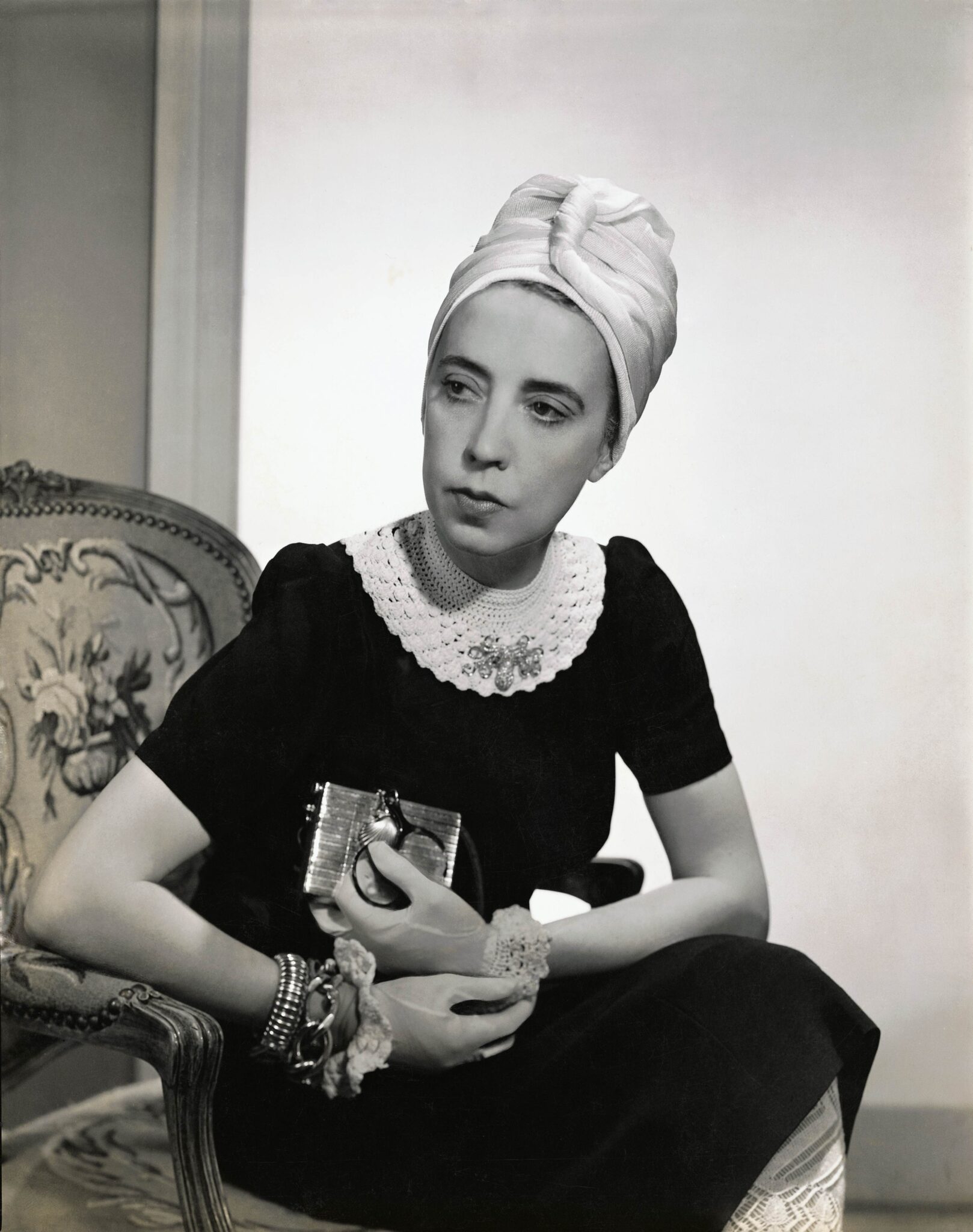 Designer Elsa Schiaparelli in a black silk dress with a crocheted collar and chuban of her own design, featured in Vogue in 1940.