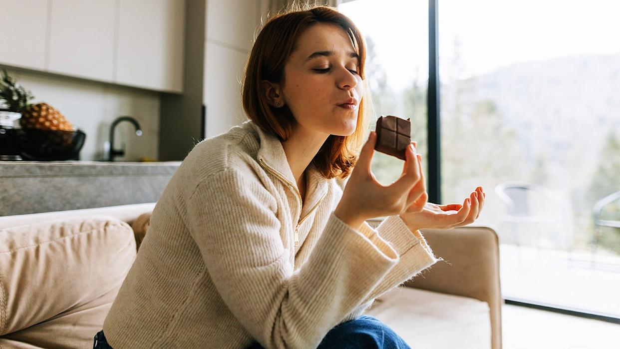 A woman enjoying chocolate on the sofa.